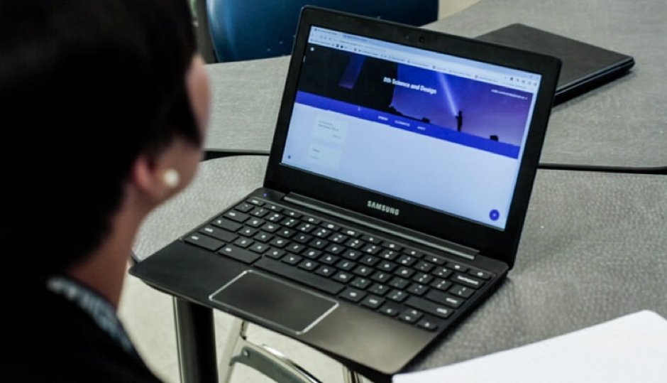 A teacher sitting in front of a laptop while connecting wirelessly using Airtame
